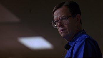 Movie still from “When a Man Falls” (2007), directed by Ryan Eslinger – A man with glasses is looking at the camera; Close Up shot, Low angle