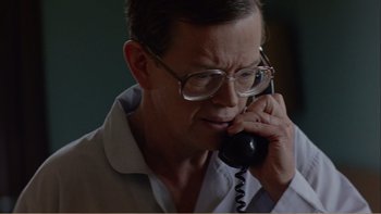 Movie still from “When a Man Falls” (2007), directed by Ryan Eslinger – A man with glasses talking on a phone; Close Up shot, Low angle