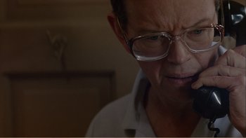 Movie still from “When a Man Falls” (2007), directed by Ryan Eslinger – An older man wearing glasses is smoking a cigarette; Close Up shot, Low angle