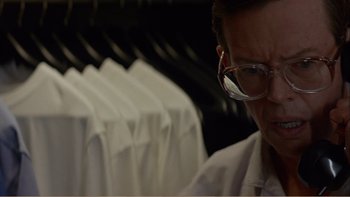 Movie still from “When a Man Falls” (2007), directed by Ryan Eslinger – A man wearing glasses looking down at a row of white shirts; Close Up shot, Over the shoulder angle