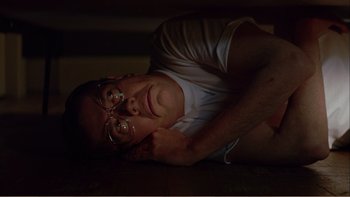 Movie still from “When a Man Falls” (2007), directed by Ryan Eslinger – A man laying on the ground with his head resting on his hand; Medium shot, Overhead angle