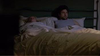 Movie still from “When a Man Falls” (2007), directed by Ryan Eslinger – A man and a woman laying in a bed together; Medium shot, Overhead angle