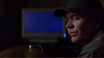 Movie still from “When a Man Falls” (2007), directed by Ryan Eslinger – A person wearing a hat and holding a wine glass; Close Up shot, Over the shoulder angle