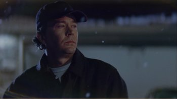 Movie still from “When a Man Falls” (2007), directed by Ryan Eslinger – A man wearing a baseball cap and a black jacket; Close Up shot, Low angle