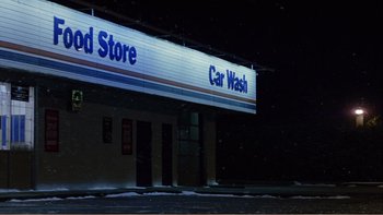 Movie still from “When a Man Falls” (2007), directed by Ryan Eslinger – A car wash sign is lit up at night; Extreme Wide shot, Low angle