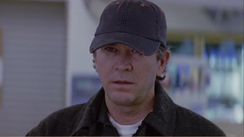Movie still from “When a Man Falls” (2007), directed by Ryan Eslinger – A person wearing a hat; Close Up shot, Over the shoulder angle