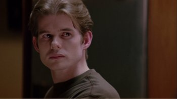 Movie still from “When a Man Falls” (2007), directed by Ryan Eslinger – A person wearing a brown t - shirt; Close Up shot, Over the shoulder angle