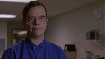 Movie still from “When a Man Falls” (2007), directed by Ryan Eslinger – A man wearing glasses and a blue shirt is smiling; Close Up shot, Low angle