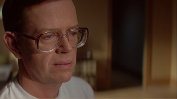 Movie still from “When a Man Falls” (2007), directed by Ryan Eslinger – A person wearing glasses and a white shirt; Close Up shot, Low angle