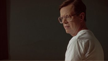 Movie still from “When a Man Falls” (2007), directed by Ryan Eslinger – An older man wearing glasses and a white shirt; Close Up shot, Over the shoulder angle