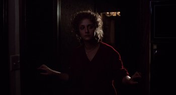 Movie still from “When a Stranger Calls” (1979), directed by Fred Walton – A woman standing in a dark room with her arms outstreched; Medium shot, Low angle
