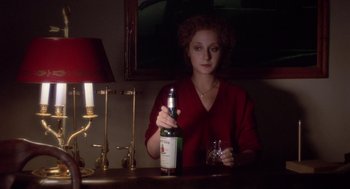 Movie still from “When a Stranger Calls” (1979), directed by Fred Walton – A woman sitting at a table holding a wine bottle; Medium shot, High angle