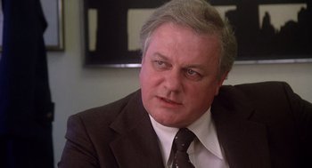 Movie still from “When a Stranger Calls” (1979), directed by Fred Walton – A man in a suit and tie sitting in front of a tv; Close Up shot, Low angle