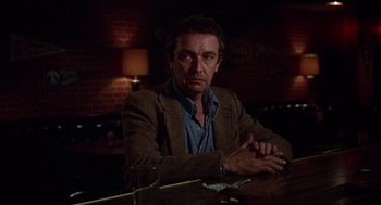 Movie still from “When a Stranger Calls” (1979), directed by Fred Walton – A man sitting at a table in front of a glass of water; Close Up shot, Low angle