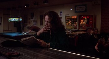 Movie still from “When a Stranger Calls” (1979), directed by Fred Walton – A woman sitting at a bar reading a newspaper; Medium shot, Low angle