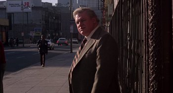 Movie still from “When a Stranger Calls” (1979), directed by Fred Walton – A man wearing a suit and tie standing on a sidewalk; Medium shot, Low angle
