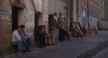 Movie still from “When a Stranger Calls” (1979), directed by Fred Walton – A group of people sitting on the side of a building; Wide shot, Low angle
