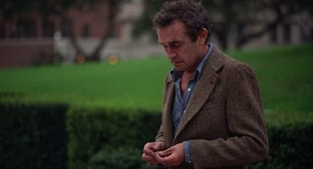 Movie still from “When a Stranger Calls” (1979), directed by Fred Walton – A man in a brown jacket is looking at his cell phone; Medium shot, High angle