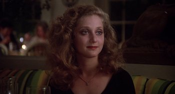 A person with curly hair wearing a necklace