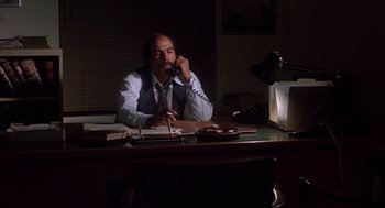 Movie still from “When a Stranger Calls” (1979), directed by Fred Walton – A man sitting at a desk talking on the phone; Medium shot, Low angle