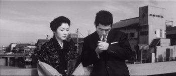 Movie still from “When a Woman Ascends the Stairs” (1960), directed by Mikio Naruse – A man and a woman are smoking a cigarette together; Medium shot, Low angle