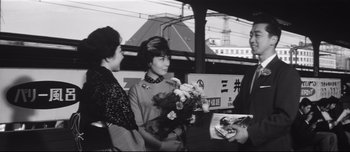 Movie still from “When a Woman Ascends the Stairs” (1960), directed by Mikio Naruse – Three women are standing in front of a train; Medium shot, Over the shoulder angle