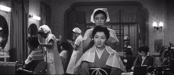 Movie still from “When a Woman Ascends the Stairs” (1960), directed by Mikio Naruse – A woman getting her hair cut by another woman; Medium shot, Low angle
