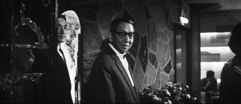 Movie still from “When a Woman Ascends the Stairs” (1960), directed by Mikio Naruse – A black and white photo of a man in a suit; Medium shot, Low angle