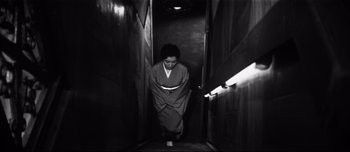 Movie still from “When a Woman Ascends the Stairs” (1960), directed by Mikio Naruse – A woman in a kimono walking down the stairs; Wide shot, High angle