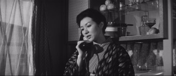 Movie still from “When a Woman Ascends the Stairs” (1960), directed by Mikio Naruse – An asian woman talking on a phone in a room; Medium shot, Low angle