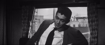 Movie still from “When a Woman Ascends the Stairs” (1960), directed by Mikio Naruse – Black and white photograph of a man in a suit and tie; Close Up shot, Low angle