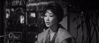 Movie still from “When a Woman Ascends the Stairs” (1960), directed by Mikio Naruse – An old photo of an asian woman in a coat; Close Up shot, High angle