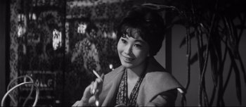Movie still from “When a Woman Ascends the Stairs” (1960), directed by Mikio Naruse – An old photo of an asian woman smoking a cigarette; Close Up shot, Low angle