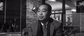 Movie still from “When a Woman Ascends the Stairs” (1960), directed by Mikio Naruse – An older man wearing a suit and a tie; Close Up shot, Low angle
