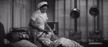 Movie still from “When a Woman Ascends the Stairs” (1960), directed by Mikio Naruse – An old photo of a woman and a man in a room; Medium shot, Low angle