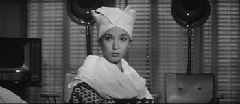 Movie still from “When a Woman Ascends the Stairs” (1960), directed by Mikio Naruse – A black and white photo of a woman wearing a head covering; Close Up shot, Low angle