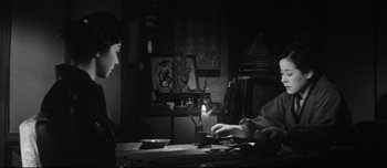 Movie still from “When a Woman Ascends the Stairs” (1960), directed by Mikio Naruse – A person sitting at a table with a candle in front of them; Medium shot, Low angle