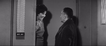 Movie still from “When a Woman Ascends the Stairs” (1960), directed by Mikio Naruse – An old photo of a man and a woman talking; Medium shot, Low angle
