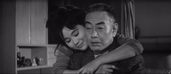 Movie still from “When a Woman Ascends the Stairs” (1960), directed by Mikio Naruse – An older man hugging a younger woman in a black and white photo; Close Up shot, Low angle