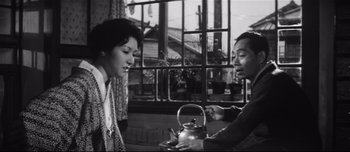 Movie still from “When a Woman Ascends the Stairs” (1960), directed by Mikio Naruse – A man and a woman holding a tea pot; Medium shot, Low angle