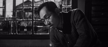 Movie still from “When a Woman Ascends the Stairs” (1960), directed by Mikio Naruse – Black and white photograph of a man looking at the camera; Close Up shot, Low angle