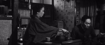 Movie still from “When a Woman Ascends the Stairs” (1960), directed by Mikio Naruse – A woman sitting in front of a tea pot on top of a table; Medium shot, High angle
