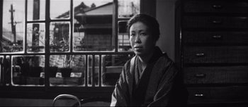 Movie still from “When a Woman Ascends the Stairs” (1960), directed by Mikio Naruse – A woman in a kimono sitting in front of a window; Medium shot, Low angle