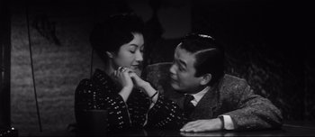Movie still from “When a Woman Ascends the Stairs” (1960), directed by Mikio Naruse – An older man and a younger woman sitting on a couch; Close Up shot, Low angle