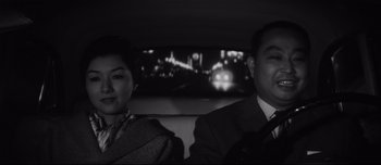 Movie still from “When a Woman Ascends the Stairs” (1960), directed by Mikio Naruse – A man and a woman sitting in the back of a car; Close Up shot, Low angle