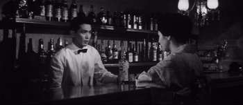 Movie still from “When a Woman Ascends the Stairs” (1960), directed by Mikio Naruse – A man sitting at a table in front of another man; Medium shot, Low angle