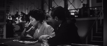 Movie still from “When a Woman Ascends the Stairs” (1960), directed by Mikio Naruse – A man and a woman sitting at a dinner table; Medium shot, High angle