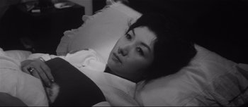 Movie still from “When a Woman Ascends the Stairs” (1960), directed by Mikio Naruse – A black and white photo of a woman laying in a bed; Close Up shot, High angle