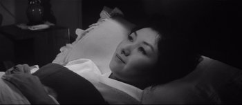 Movie still from “When a Woman Ascends the Stairs” (1960), directed by Mikio Naruse – A black - and - white photo of a woman laying in bed; Close Up shot, High angle
