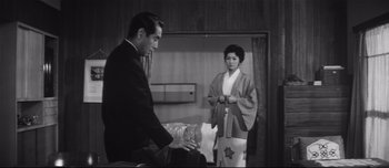 Movie still from “When a Woman Ascends the Stairs” (1960), directed by Mikio Naruse – A man and a woman standing next to each other in a room; Medium shot, Low angle